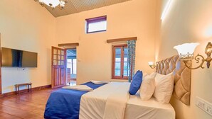 Un dormitorio con cama, televisión, ventana y puerta.