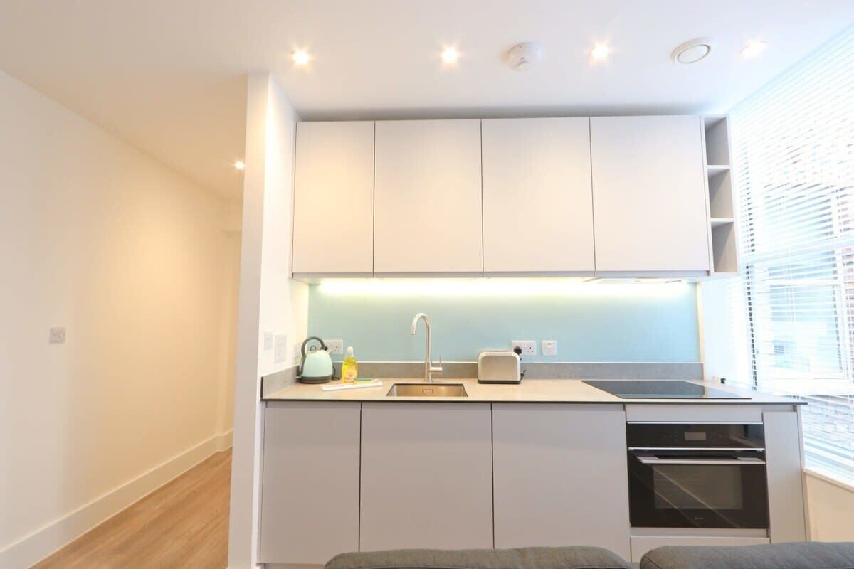 A compact kitchen with a sink, toaster, kettle, and oven.