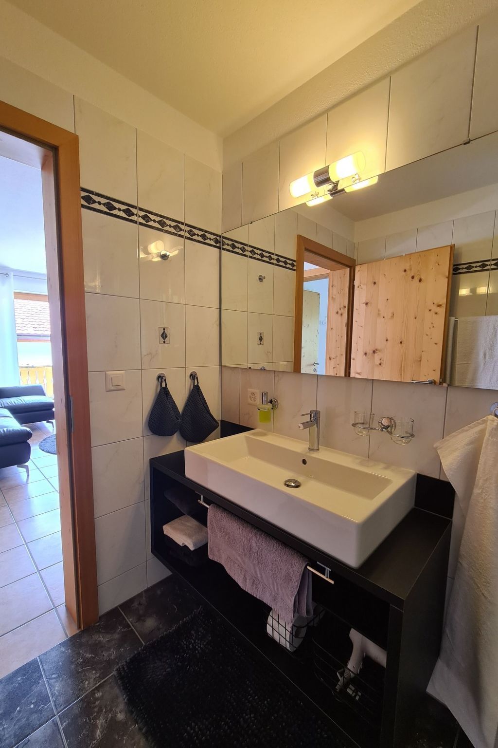 Un bagno moderno con un lavandino capiente, uno specchio e un portasciugamani.