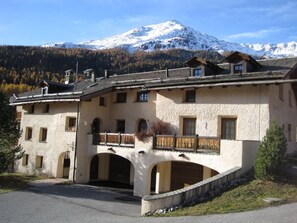 Un chalet traditionnel avec une façade en pierre, de nombreux balcons et une entrée en arc de cercle.