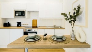 Cozinha moderna com armários brancos, micro-ondas embutido e bancada de madeira.