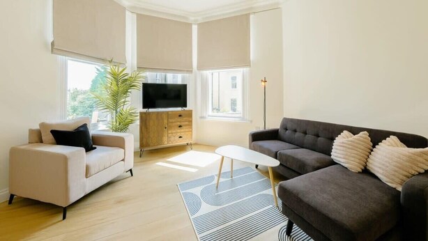 Uma sala de estar moderna com sofá, mesa de centro, televisão e uma planta.