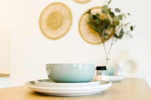 Ein Tisch mit Schüssel und Untertasse, eine Vase mit Grünpflanzen und eine Wand mit runden Verzierungen.