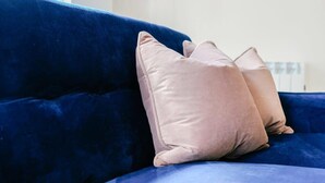 Een blauwe bank met twee beige kussens.