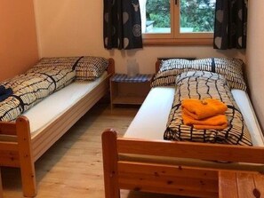 A room with two wooden beds, each with patterned bedding and pillows. - Chalchera, (Ftan) by Interhome (Ftan)