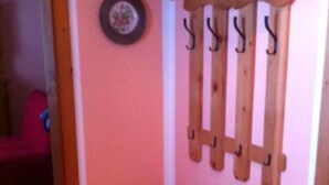 Un banc en bois avec des crochets fixés au mur, une porte et un mur rose.