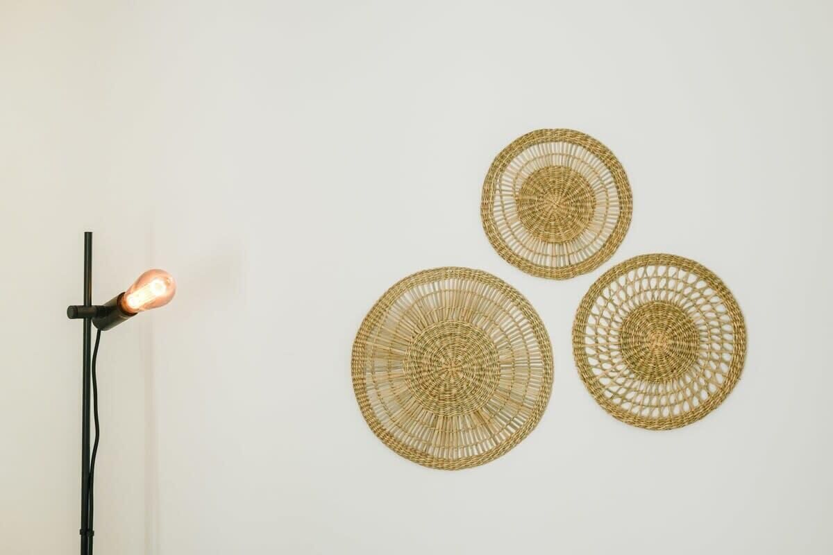 Eine Wand mit drei runden Wandteppichen und einer Stehlampe mit aufleuchtender Glühbirne.