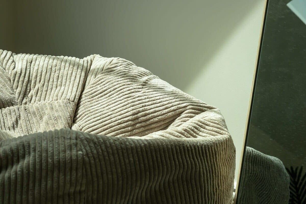 Gros plan d’un fauteuil de couleur beige à motifs en relief, doté d’une surface lisse et réfléchissante.