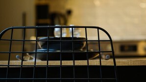 A kitchen with a metal grid barrier, a stove, and a blurred background. - Hotwells apartments flat 1 - Hopewell (Bristol)