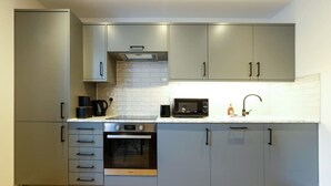 A modern kitchen with grey cabinets, a built-in oven, a microwave, and a stainless steel range hood. - Hotwells apartments flat 1 - Hopewell (Bristol)