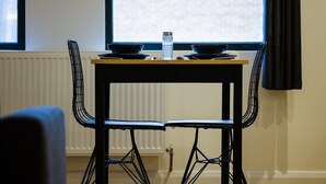 A dining table with two chairs, a water bottle, and a window with curtains. - Hotwells apartments flat 1 - Hopewell (Bristol)