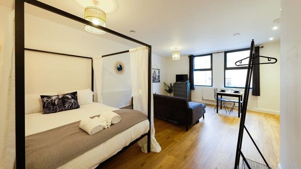 A bedroom with a four-poster bed, a desk, and a chair in the adjacent room. - Hotwells apartments flat 1 - Hopewell (Bristol)