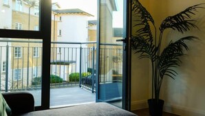 Un balcone con vista sugli edifici, una pianta in vaso e una porta che dà sull'esterno.