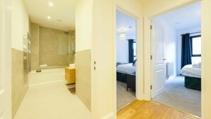 Camera d'albergo con doccia, vasca da bagno, un letto e una piccola area salotto.