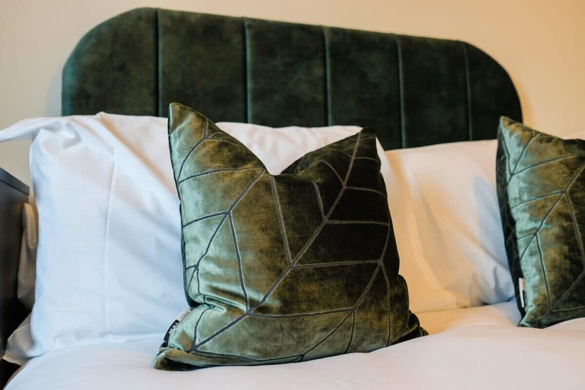 A bed with a dark headboard and two decorative pillows.