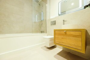 Une salle de bain moderne comprenant une baignoire, des toilettes, un meuble-lavabo en bois avec un miroir et un espace douche.