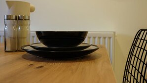 A wooden table with a black bowl and plate, a cream-colored pitcher, and two metallic containers. - Hotwells apartments flat 2 - Hopewell (Bristol)