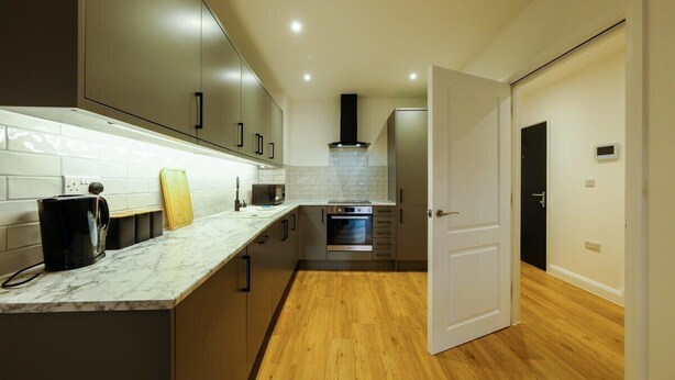 A modern kitchen with a marble countertop, built-in oven, and wooden flooring. - Hotwells apartments flat 2 - Hopewell (Bristol)