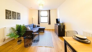 A modern living room with a sofa, a dining table, a potted plant, and a radiator. - Hotwells apartments flat 2 - Hopewell (Bristol)