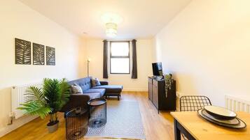 Un salon moderne avec un canapé, une table à manger, une plante en pot et un radiateur.