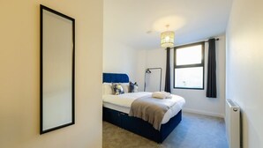 A bedroom with a bed, a bedside lamp, a window with curtains, and a radiator. - Hotwells apartments flat 2 - Hopewell (Bristol)