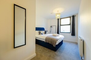 Une chambre à coucher avec un lit, une lampe de chevet, une fenêtre avec des rideaux et un radiateur.
