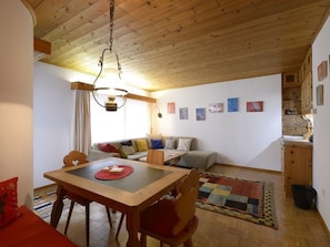 Una habitación acogedora con techo de madera, una mesa de comedor con sillas, un sofá y una alfombra.