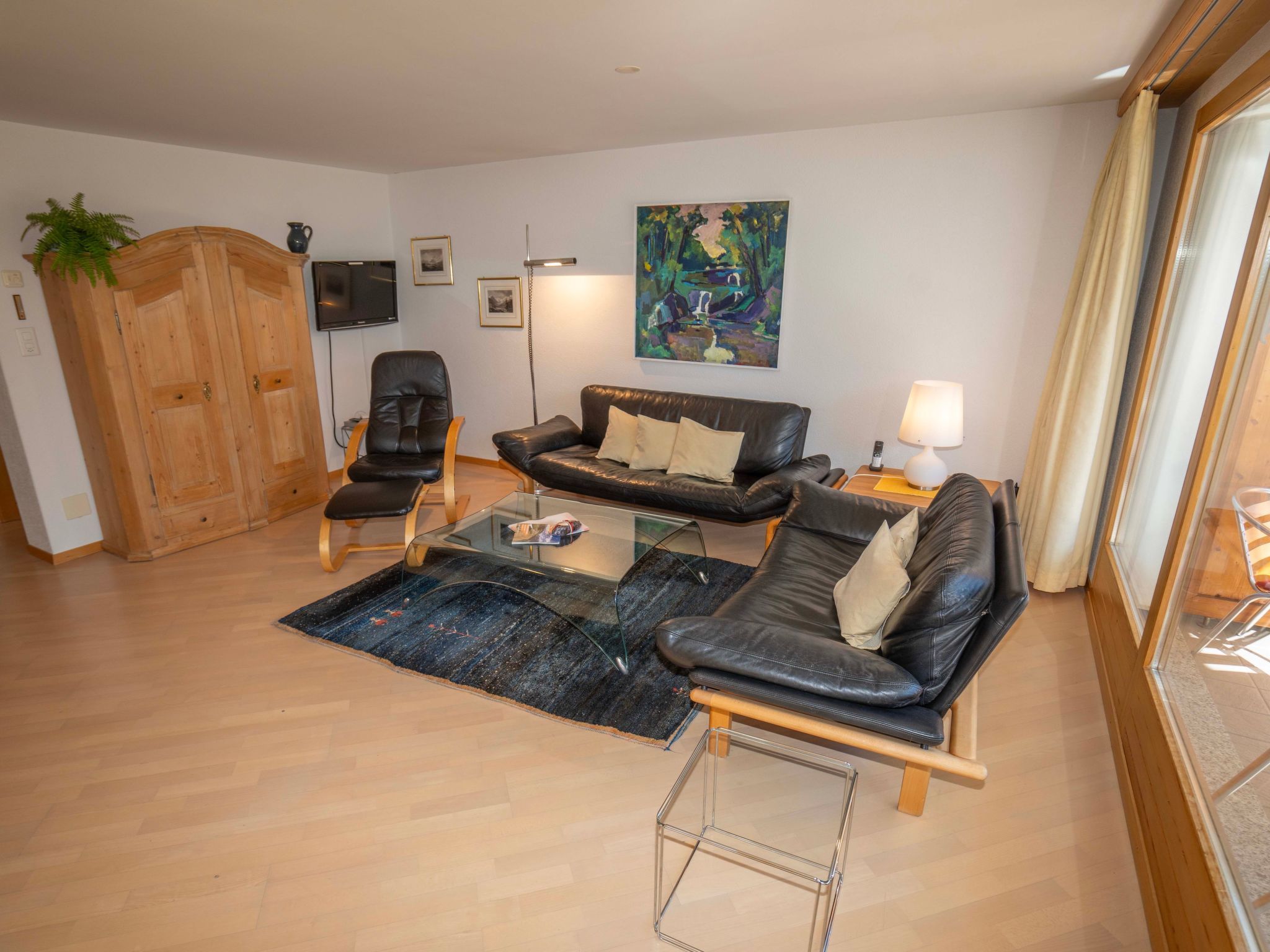 A living room with a sofa, armchairs, a coffee table, a TV, and artwork on the wall.