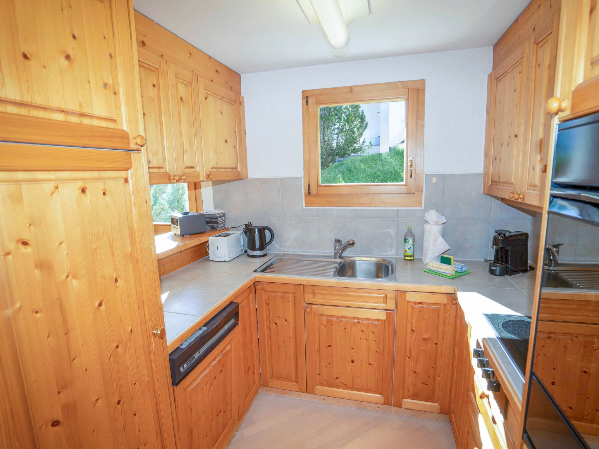 Una cocina con armarios de madera, una ventana, un lavamanos y un lavavajillas.