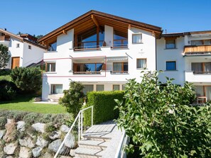 Ein mehrstöckiges Wohngebäude mit Holzfassade, großen Fenstern und einem gepflegten Garten.