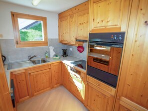 Eine Küche mit Holzausstattung, einer Edelstahlspüle und einem eingebauten Backofen.