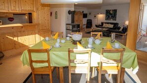 Zona pranzo con tavolo apparecchiato per quattro persone, sedie in legno e tovaglia verde.