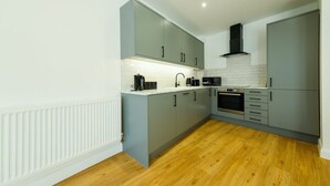 A modern kitchen with grey cabinets, a white countertop, and a wooden floor. - Hotwells apartments flat 6- Hopewell (Bristol)
