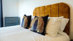 A bed with a headboard, two decorative pillows, a white bedspread, and a small bedside table. - Hotwells apartments flat 6- Hopewell (Bristol)
