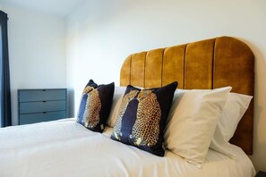 A bed with a headboard, two decorative pillows, a white bedspread, and a small bedside table. - Hotwells apartments flat 6- Hopewell (Bristol)