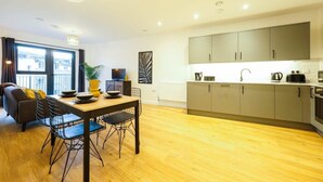 A modern apartment with a dining area, kitchen, and a large window with curtains. - Hotwells apartments flat 6- Hopewell (Bristol)