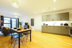 A modern apartment with a dining area, kitchen, and a large window with curtains. - Hotwells apartments flat 6- Hopewell (Bristol)