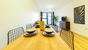A dining area with a wooden table, black wire chairs, and a yellow vase centerpiece. - Hotwells apartments flat 6- Hopewell (Bristol)