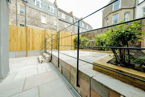 A courtyard with a wooden fence, a staircase, and a garden area with plants.