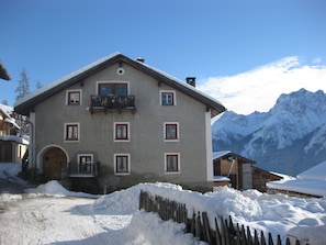 A two-story building with a balcony, surrounded by snow and mountains. - Chasa Munt Fallun 3, (Ftan) by Interhome (Ftan)