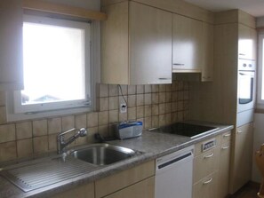 Eine Küche mit Fenster, Edelstahlspüle und weißen Schränken.