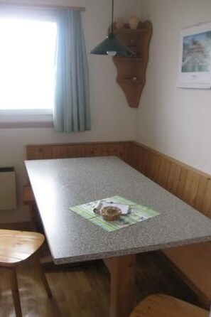 A room with a wooden bench, a table, and a hanging light fixture. - Chasa Munt Fallun 3, (Ftan) by Interhome (Ftan)
