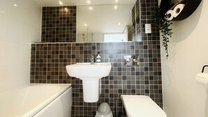A bathroom with a white sink, toilet, and bathtub, tiled walls, and a mirror. - The Robinson Building (Bristol City)