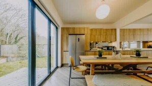 Eine moderne Küche mit Holzschränken, einem Esstisch mit Stühlen und einem großen Fenster.