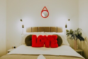 A bed with a headboard, a red pillow with the word 'LOVE,' a small mirror, and a plant on a bedside table. - Spacious Unicorn House, All Events Welcome! (Bristol City)