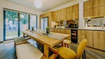 A modern kitchen with wooden cabinets, a central island, and a dining area with a bench and chairs.