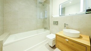 Une salle de bain moderne avec une douche à parois de verre, une baignoire blanche, des toilettes et un meuble-lavabo en bois avec un lavabo blanc.