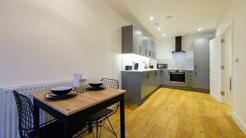 A compact kitchen with grey cabinets, a wooden dining table, and a black chair.