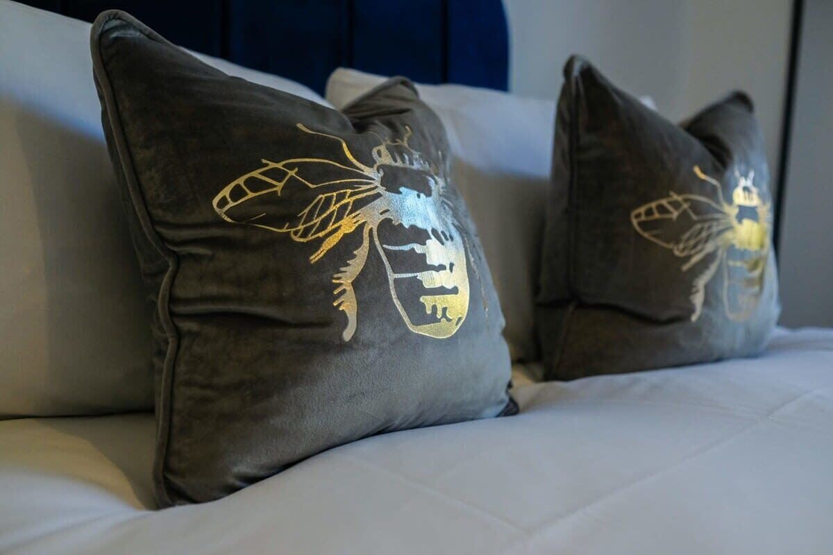 Dos almohadas con un diseño de abeja sobre una cama.