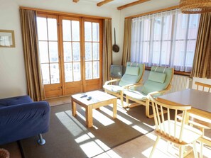 A living room with a sofa, two armchairs, a coffee table, a television, and large windows with curtains. - Ferienhaus Chasa Allegra, (Scuol) by Interhome (Scuol)